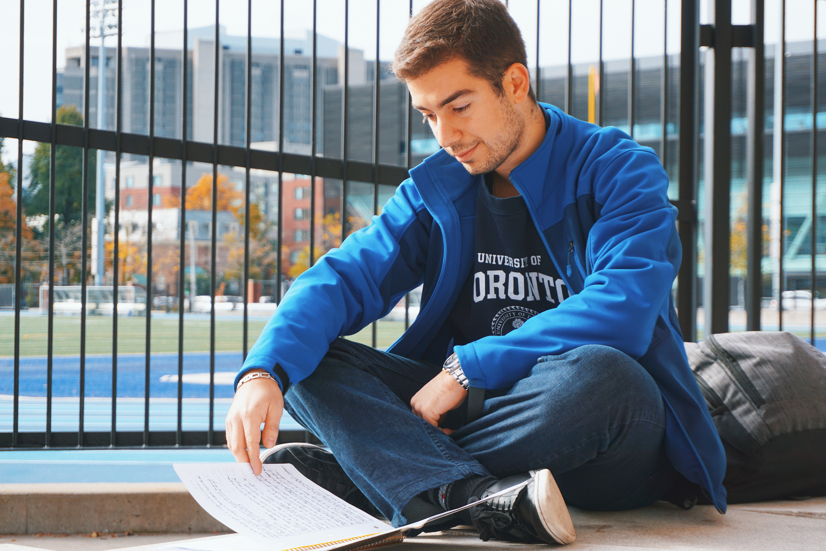 Photo of a male student studying outside Varsity Stadium