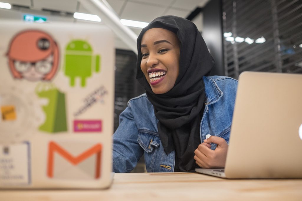 U of T student smiles while looking at a laptop