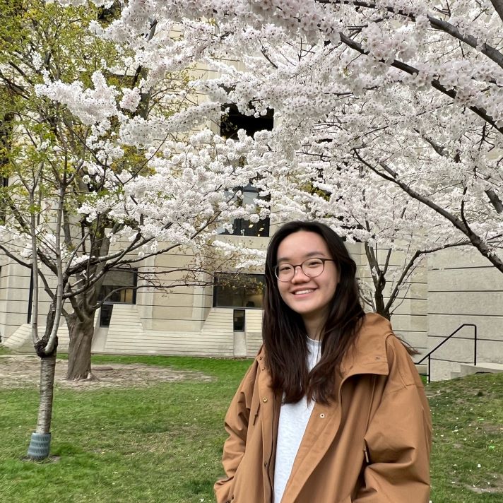 Charlotte posing in front of the cherry blossom trees at Robarts
