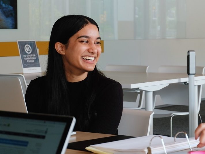 Student smiles as they chat with someone off camera.